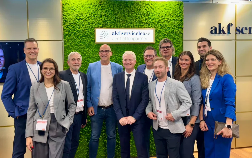 Gruppe von neun Personen in Businesskleidung vor einer grünen Wand mit dem Schild akf servicelease der flottenpartner