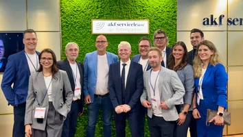 Gruppe von neun Personen in Businesskleidung vor einer grünen Wand mit dem Schild akf servicelease der flottenpartner