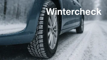 Nahaufnahme eines Autoreifens mit Winterprofil auf verschneiter Straße mit dem Text Wintercheck