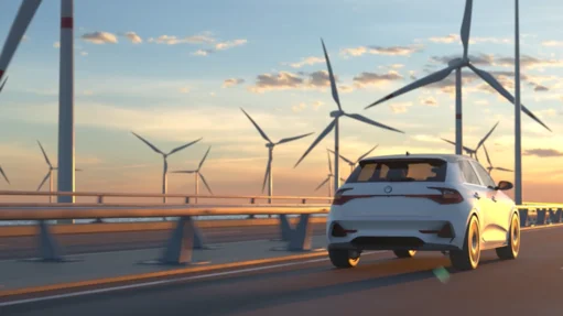 Ein weißes Auto fährt auf einer Brücke mit Windrädern im Hintergrund bei Sonnenuntergang