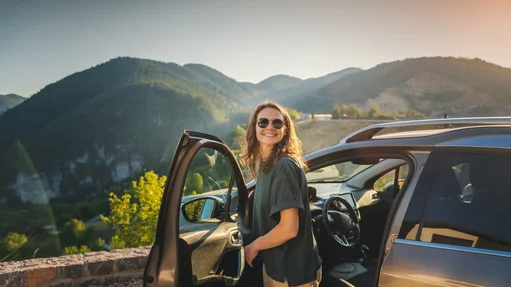 Eine Frau steigt aus einem Auto aus, im Hintergrund is eine Berglandschaft zu sehen